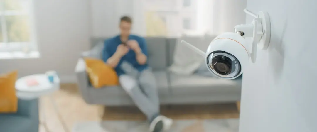 Man Sat On Sofa Viewing Cctv Footage On His Phone